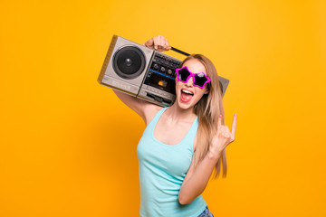 Stylish and young fashion blonde giving the Rock and Roll sign and holds a tape recorder on her...