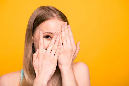 Close up portrait of young model woman close her eyes with palms, peeking out open fingers isolated on bright yellow background with copy space for text