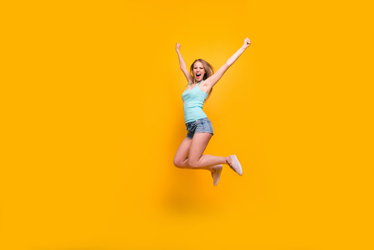 Full-legh portrait of cute blondy girl happily jump and rejoices of victory rise up fists isolated on bright yellow background with copy space for text