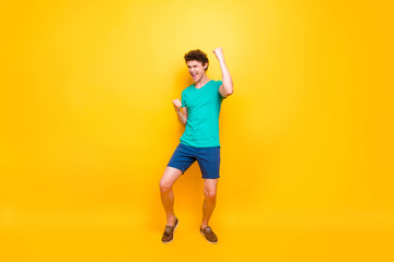 Fototapeta na wymiar Young attractive handsome cheerful guy wearing casual green polo t-shirt and blue shirts, raising hands up celebrating winning. Isolated over vivid shine bright yellow background