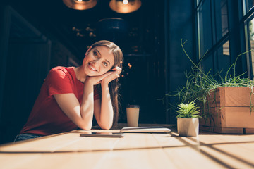 Attractive nice smiling happy young girl freelancer student wearing casual sitting in cafeteria,  drinking coffee, dark interior