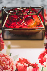 Rings on rose petals inside of handmade forged metal and glass transparent box