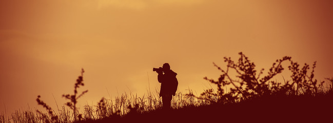 Fototapeta na wymiar Photographer Takes Pictures in the Wild. Web Banner. Photographing Safari Camera Horizontal 