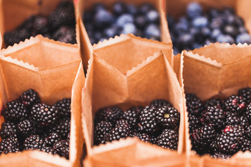 Fresh blackberry and blueberry in small craft paper boxes on wedding reception table, rustic style, summer mood