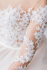 Lace details of white wedding dress closeup, hands of bride