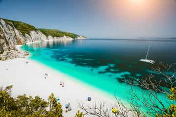 Fototapeta na wymiar Paradise beach with clear azure emerald sea water surrounded by high white rocky cliffs. Fteri beach in Kefalonia Island, Greece
