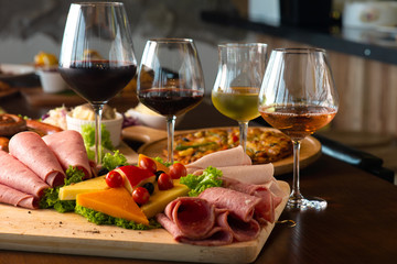 Antipasti platter with different meat and cheese products on wooden board
