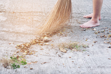 Man cleaning outdoor road using bloom made from dry coconut leave product - local people lifestyle...