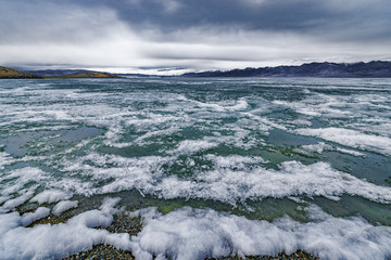Scenic view of frozen wild lake under stormy sky
