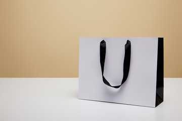 one white shopping bag on white table isolated on beige