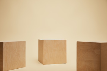 three brown wooden cubes isolated on beige