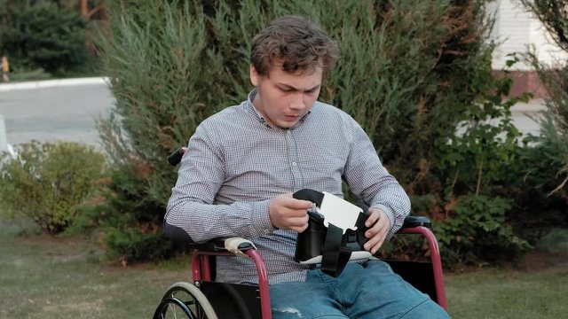 A disabled man in a wheelchair chair dresses a virtual reality helmet