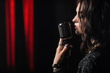 Portrait of beautiful woman singing in microphone
