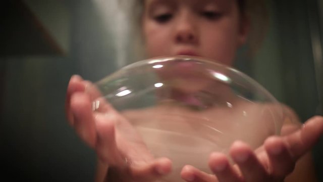 Child Girl Play Make Blow Big Soap Bubbles With Her Hands In Bathroom, Stretch, Collide And Burst Them