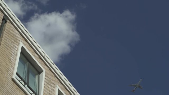Plane flies far away in sky above house