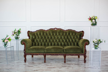 Luxurious green sofa, in white room with flowers