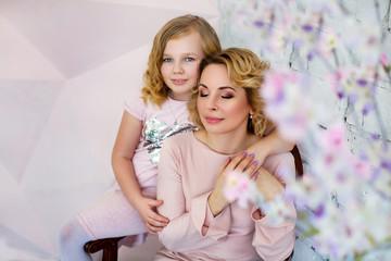 Portrait of mother and daughter, together hugging near flowers