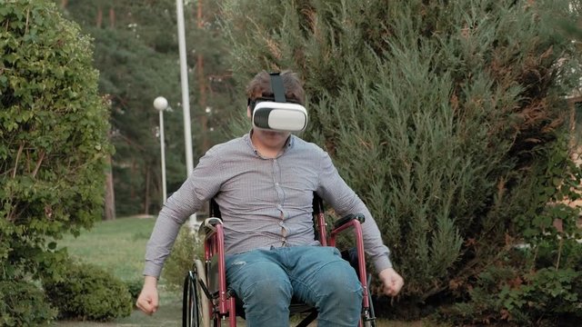 A disabled man in a wheelchair chair uses a virtual reality helmet