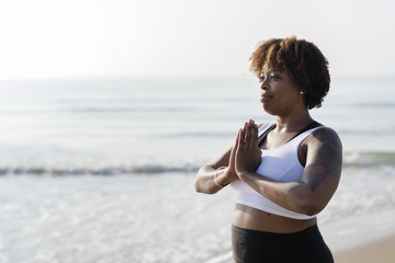 African American woman practicing yoga at the beach - obrazy, fototapety, plakaty