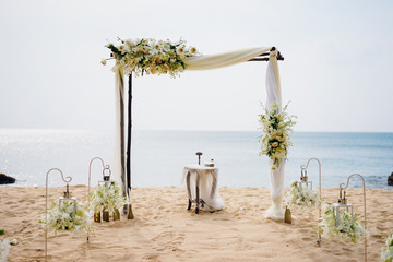 A gentle wedding arch on the sandy shore of the Ocean. Wedding ceremony in a tropical style.