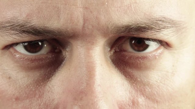 Extreme close up of man eyes looking furious and angry