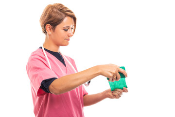 Side view of female vet wearing pink scrub using green bandage.