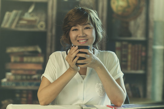 Asian Woman 50s Year Old Toothy Smiling Face White Beverage Cup In Hand