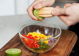 Man preparing mango salsa, squeezing lime juice