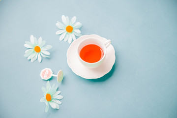 Morning cup of red tea on the table top view in flat lay pastel style .Beautiful breakfast and Daisy flower