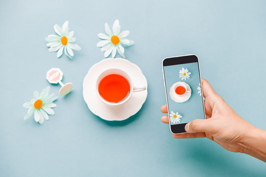 Hands taking photo to Cup of red Tea Berry with cell telephone or smartphone digital camera for Post to Social Network and Social Media Online on the Internet . Customise pastel bright colors tone . - Powered by Adobe