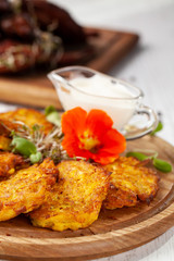The concept of Ukrainian cuisine. Draniki from potatoes and pumpkins, with edible flowers. Copy space, selective focus