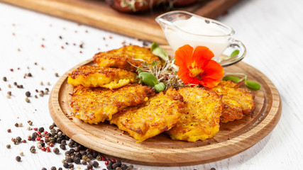 The concept of Ukrainian cuisine. Draniki from potatoes and pumpkins, with edible flowers. Copy space, selective focus