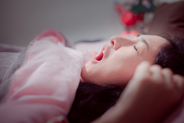 Snore problem concept. Asian women sleeping with her mouth open and snoring loudly .