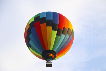 Fototapeta premium kolorowy balon na ogrzane powietrze przeciw błękitne niebo. w białych chmurach leci balon na ogrzane powietrze. piękne latanie balonem