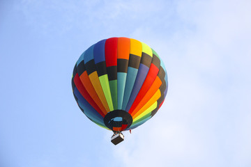 Fototapeta premium colorful hot air balloon against blue sky. hot air balloon is flying in white clouds. beautiful flying on hot air balloon