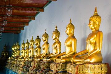 Aligned golden Buddha statues in a temple, Thailand.
