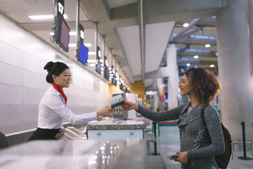 Airline check in attendant handing passport to commuter