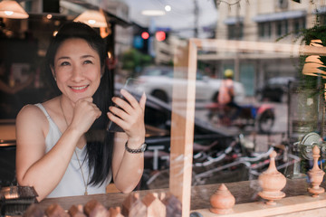 Fototapeta na wymiar Beautiful Asian women Using smart Phone with Cup of Tea Emotional happiness on table in cafe restaurant or coffee shop .Post to Social Network and Social Media Online Internet On table in holiday.