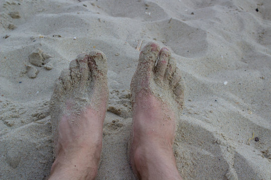men's feet on the beach