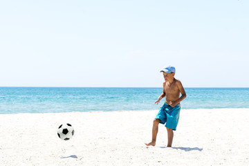 A boy playing football at the empty beach