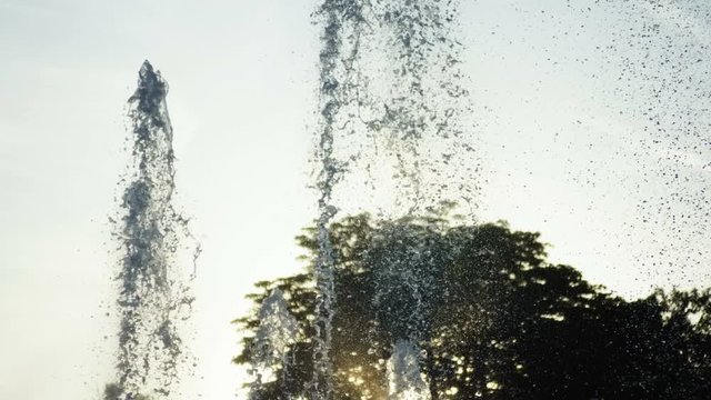 Close-up shot of water drops of fountain in summer park at sunset. 4K