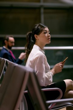 Young woman using cell phone while sitting at airport