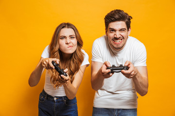 Excited tense man and woman playing together and competing in video games using joysticks, isolated...
