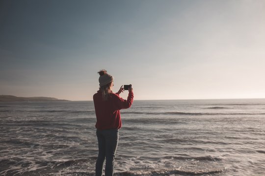 Woman taking photo with mobile phone at beach