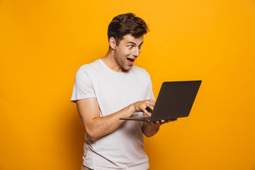 Portrait of a cheerful young man using laptop computer