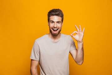 Portrait of a happy young man showing ok gesture - obrazy, fototapety, plakaty