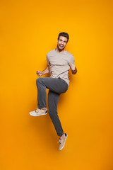 Fototapeta na wymiar Full length portrait of a cheerful young man jumping