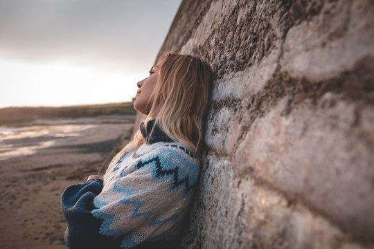 Thoughtful woman leaning against wall on beach