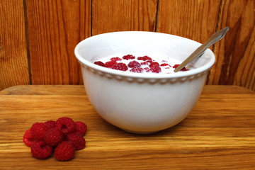 raspberry ripe juicy floats in milk in a plate with a spoon