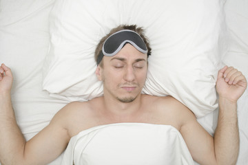 Man resting in a mask for sleep. Stubble on his face. Tired man